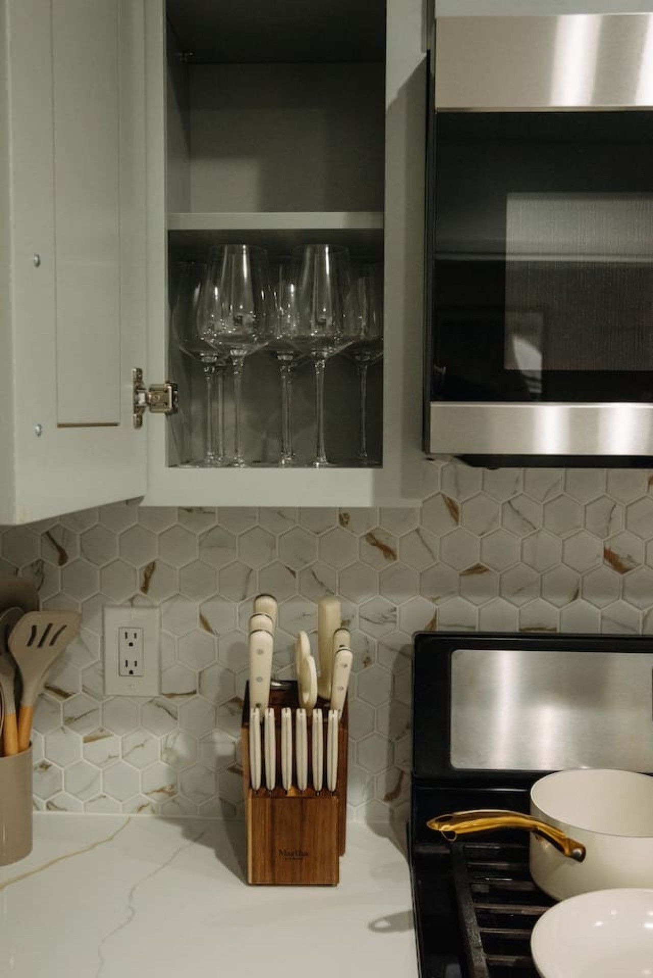 A kitchen with a hexagonal tile backsplash, a knife block, and a microwave.