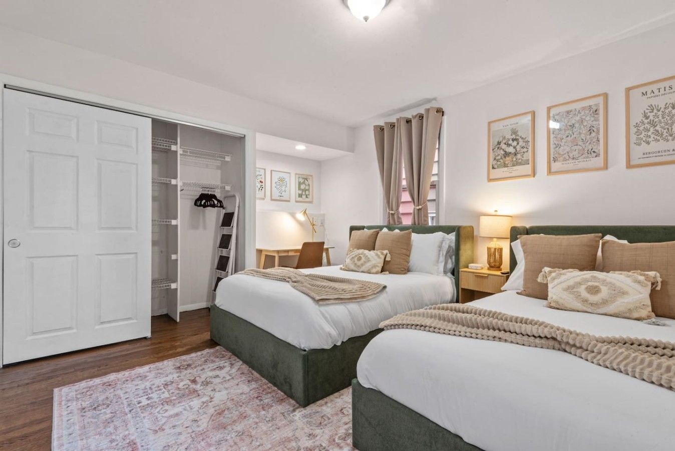 Una habitación de hotel con dos camas, un armario, un escritorio y una silla.