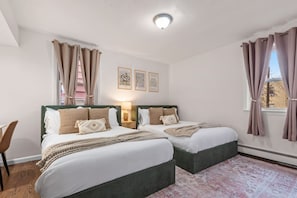 Habitación doble con cama, mesitas de noche y ventana con cortinas.
