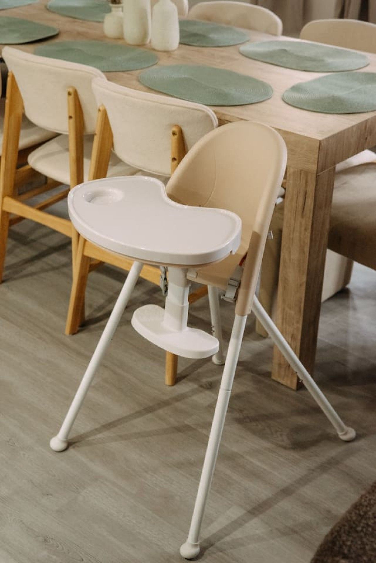 A dining table with a high chair and a bottle of water.