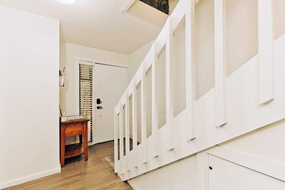 A hallway with a wooden floor, white walls, and a door with a window.