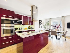A modern kitchen with built-in appliances and a dining area with a view. - Westminster Duplex 2BR Apartment with Balcony (Greater London)