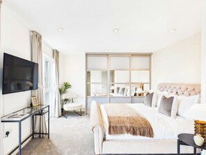 Ein Hotelzimmer mit Bett, Fernseher, Schreibtisch und einem großen Spiegel.