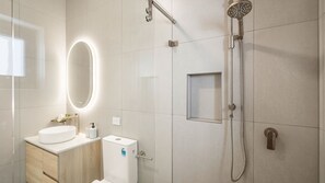Ein modernes Badezimmer mit einem weißen Waschbecken, einem Spiegel, einer Handbrause und einer Toilette.