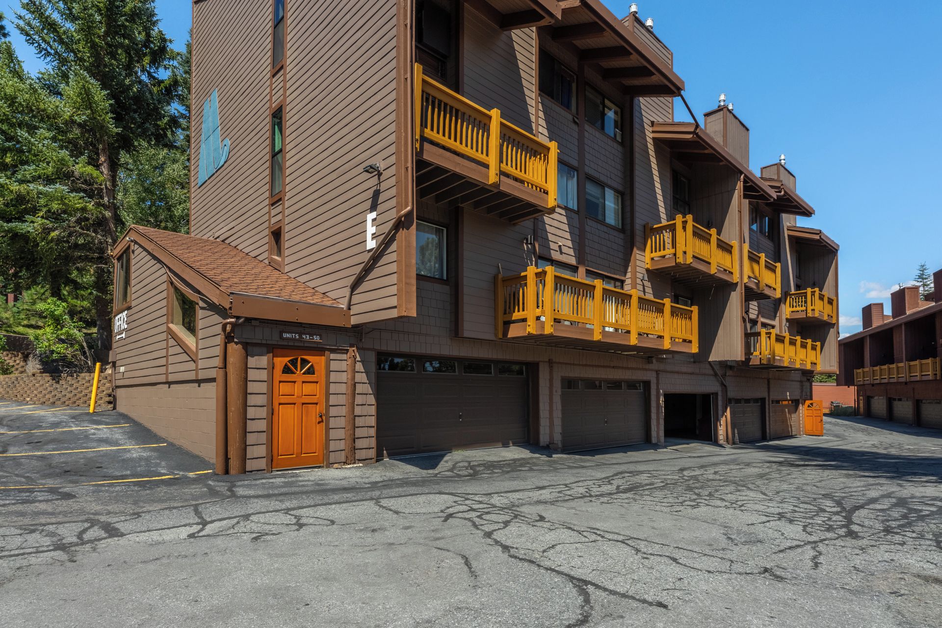 A multi-story building with a brown facade, yellow balconies, and a garage entrance.