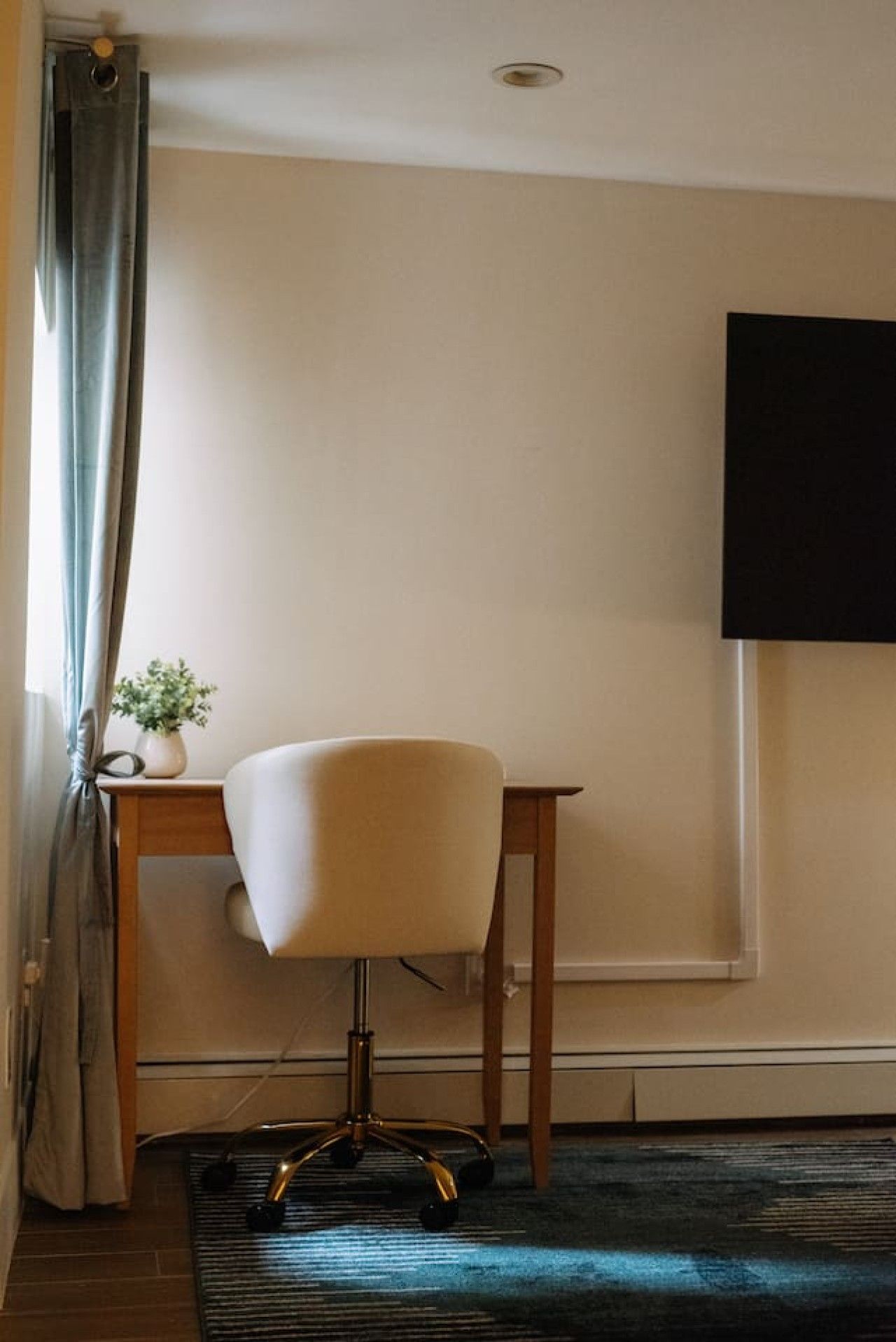 Quarto com escrivaninha, cadeira e planta em vaso.