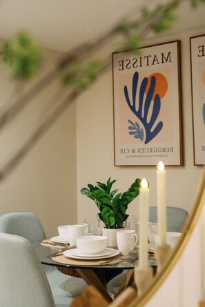 Un comedor con una mesa dispuesta para dos, una planta en maceta y dos velas encendidas.