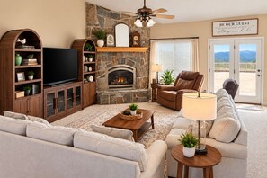 A living room with a stone fireplace, a television, a leather recliner, and a sofa.