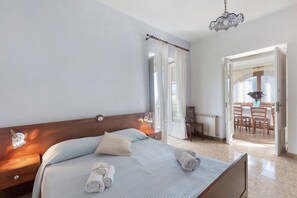 Ein Hotelzimmer mit Bett, Nachttischen, einer Hängelampe, Blick auf den Essbereich und einer Tür, die nach draußen führt.