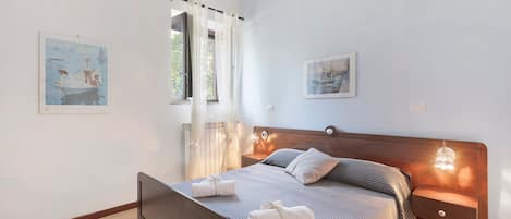 A bedroom with a bed, bedside tables, a headboard, and artwork on the walls.