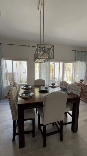 Zona pranzo con tavolo in legno, sei sedie e lampadario.