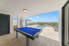A pool table with a clear view of a swimming pool and a scenic landscape. - Cliffside Oasis-The Villa Private gym/pool-Seaview (Sint Michiel)