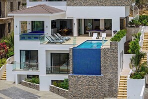A modern multi-story house with a rooftop pool, glass railings, and a stone facade. - Cliffside Oasis-The Villa Private gym/pool-Seaview (Sint Michiel)
