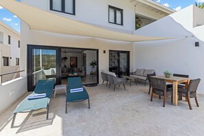 A sunlit outdoor patio area with a dining table, chairs, and lounge chairs. - Casa Quince - Greenview - Sea View Retreat (Sint Michiel)