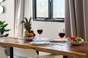A dining table with a fruit bowl, two wine glasses, and plates. - Casa Quince - Greenview - Sea View Retreat (Sint Michiel)