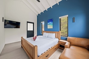 A bedroom with a wooden bed, a TV mounted on the wall, and a large window with a view of trees. - Cliffside Penthouse - Private Pool - Seaview - Bluebay (Sint Michiel)