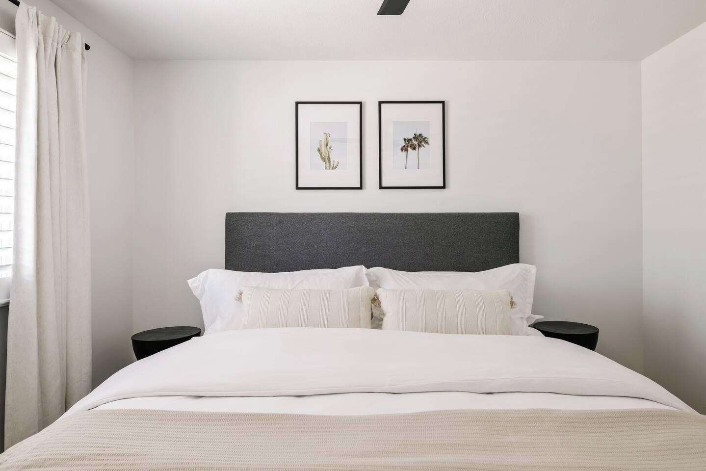 A bedroom with a bed, two nightstands, a headboard, and two framed pictures on the wall.