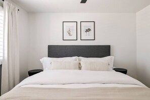 A bedroom with a bed, two nightstands, a headboard, and two framed pictures on the wall.