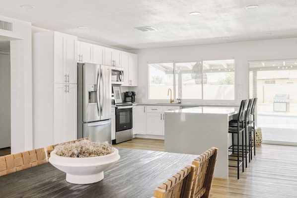 A modern kitchen with white cabinetry, stainless steel appliances, and a central island.