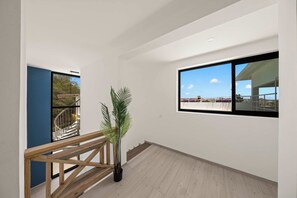 Ein modernes Interieur mit einer Holztreppe, einem Topfpflanzen und einem großen Fenster mit Blick ins Freie.
