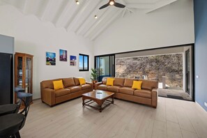 Ein modernes Wohnzimmer mit einer Eckcouch, einem Couchtisch und einem großen Fenster mit Blick ins Freie.