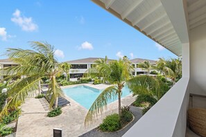 Ein modernes Resort mit Swimmingpool, Palmen und blauem Himmel.