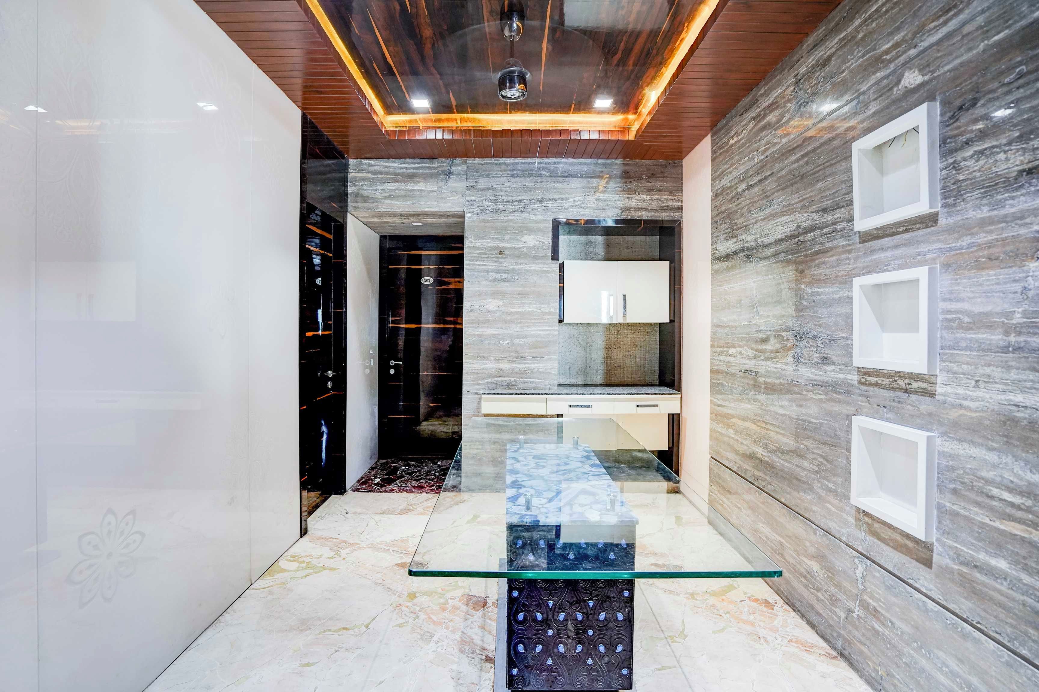 Ein modernes Interieur mit einem Glastisch, einer Holzbalkendecke und einer Marmorwand.