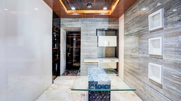Un interior moderno con una mesa de centro de vidrio, techo de madera y pared de mármol.