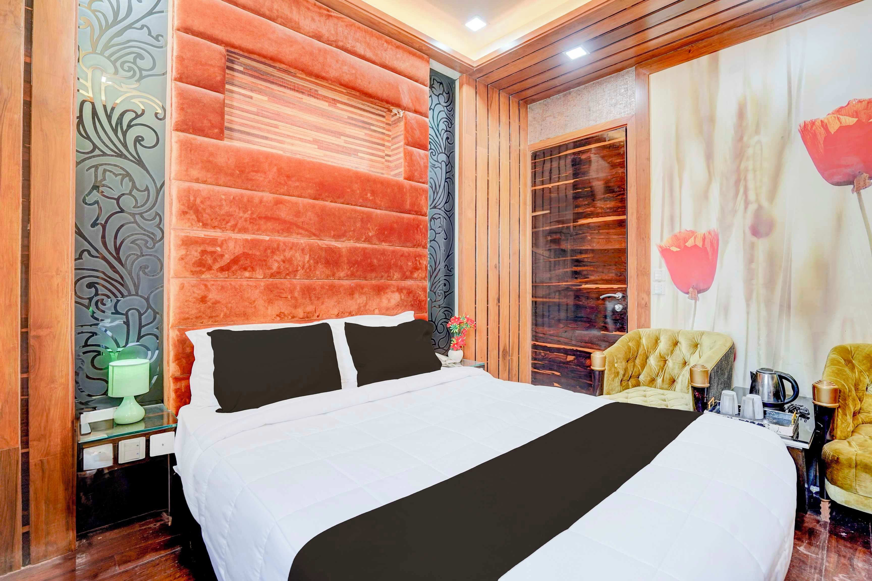 Une chambre d’hôtel avec un grand lit, une table de chevet, une lampe, une chaise et un mur décoratif.