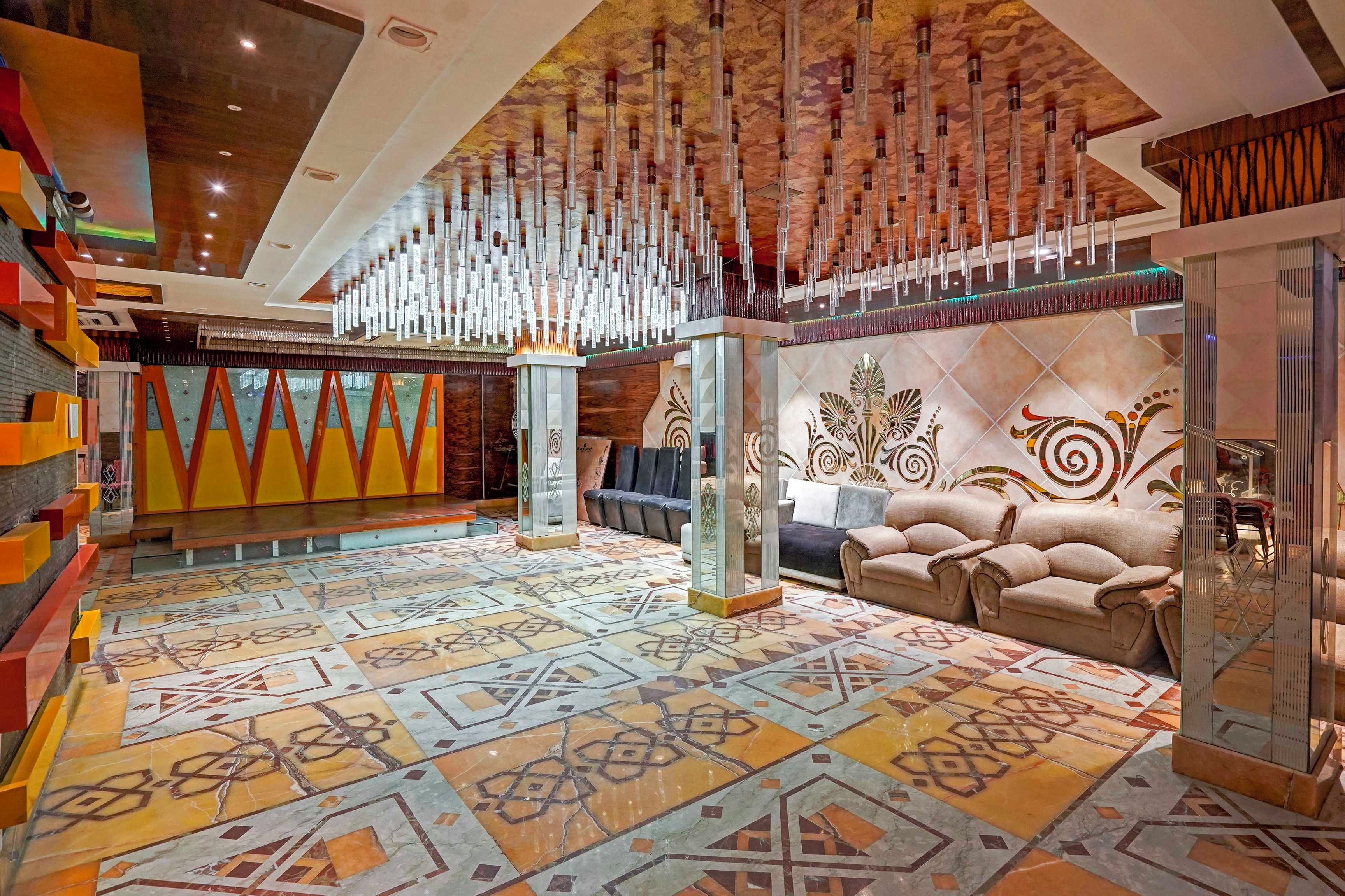 Un hall d’entrée spacieux avec un sol à motifs, un coin salon avec des canapés et un plafond décoratif.
