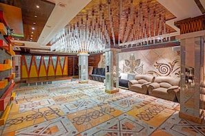 Un hall amplio con piso estampado, una zona de estar con sofás y un techo decorativo.