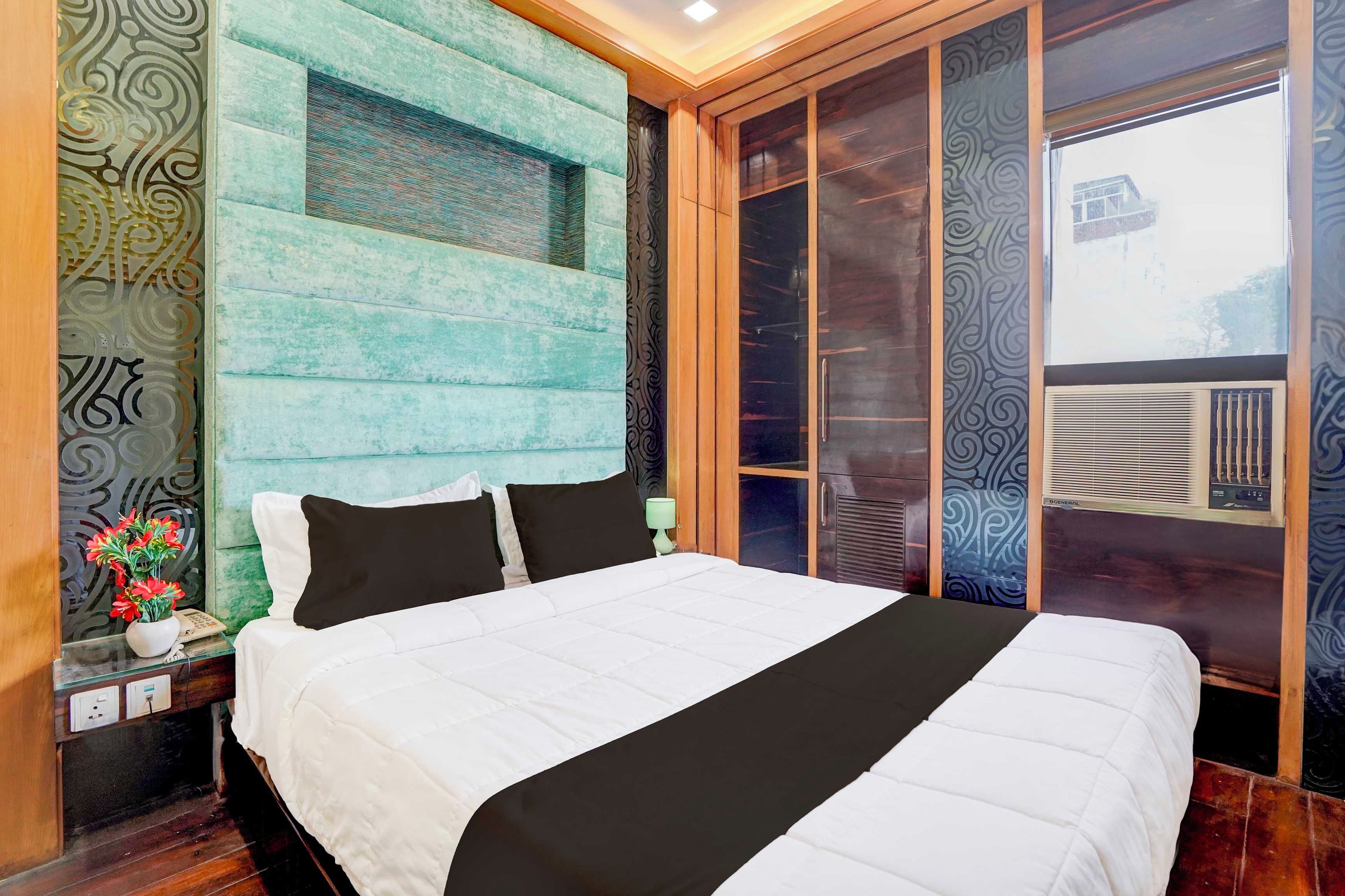Ein Hotelzimmer mit Bett, Nachttisch, Blumen in einer Vase und einem Fenster mit Blick.
