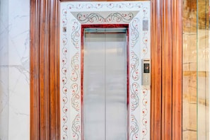 Un ascensor con un motivo floral decorativo en las paredes y una pantalla digital que muestra el número 2.