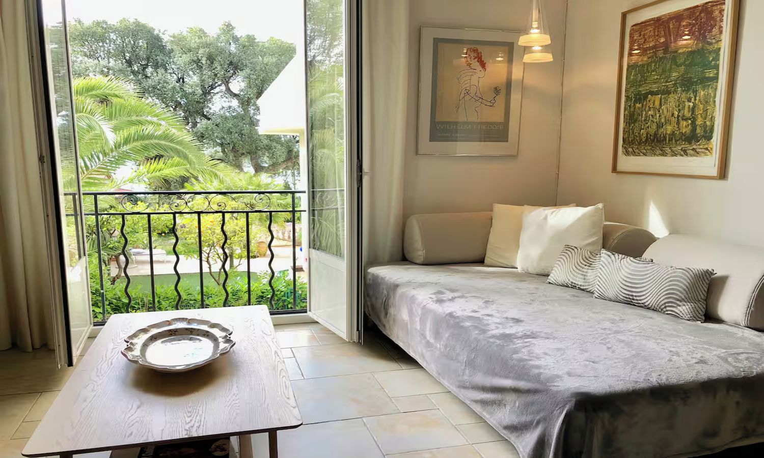 Une chambre avec un lit, une table avec une assiette, un balcon avec une balustrade et un tableau au mur.