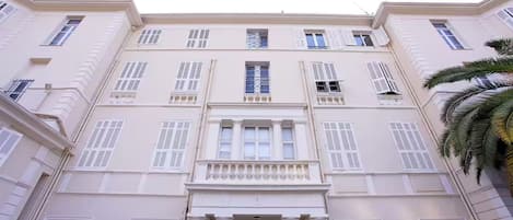 Un edificio de varios pisos con fachada simétrica, amplias ventanas y una entrada central con columnas.
