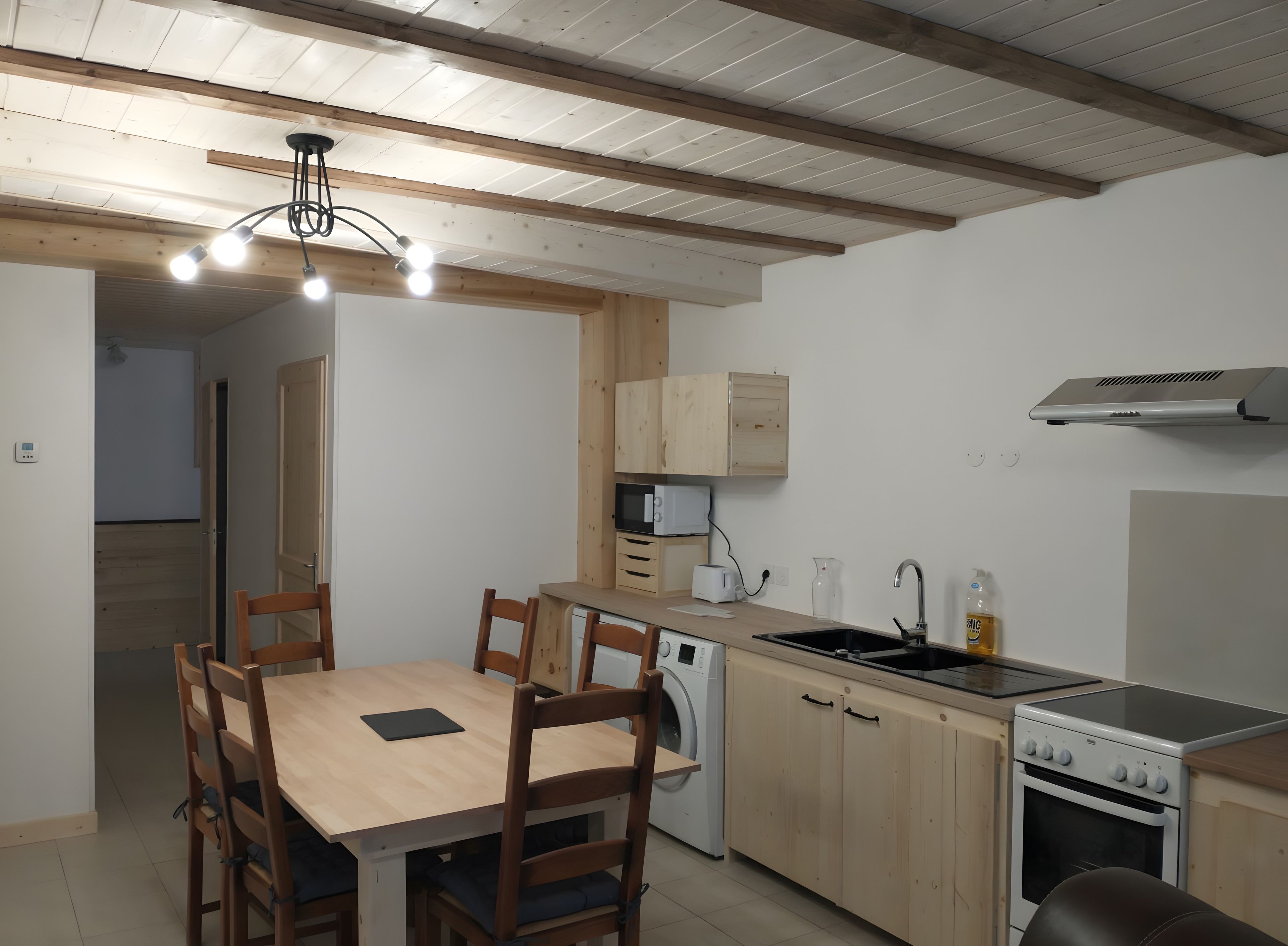 A compact kitchen with wooden cabinets, a built-in oven, and a dining area with a table and chairs.