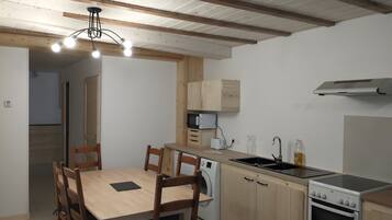 A compact kitchen with wooden cabinets, a built-in oven, and a dining area with a table and chairs.