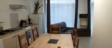A compact kitchen with a dining area, wooden furniture, and a large window with curtains.