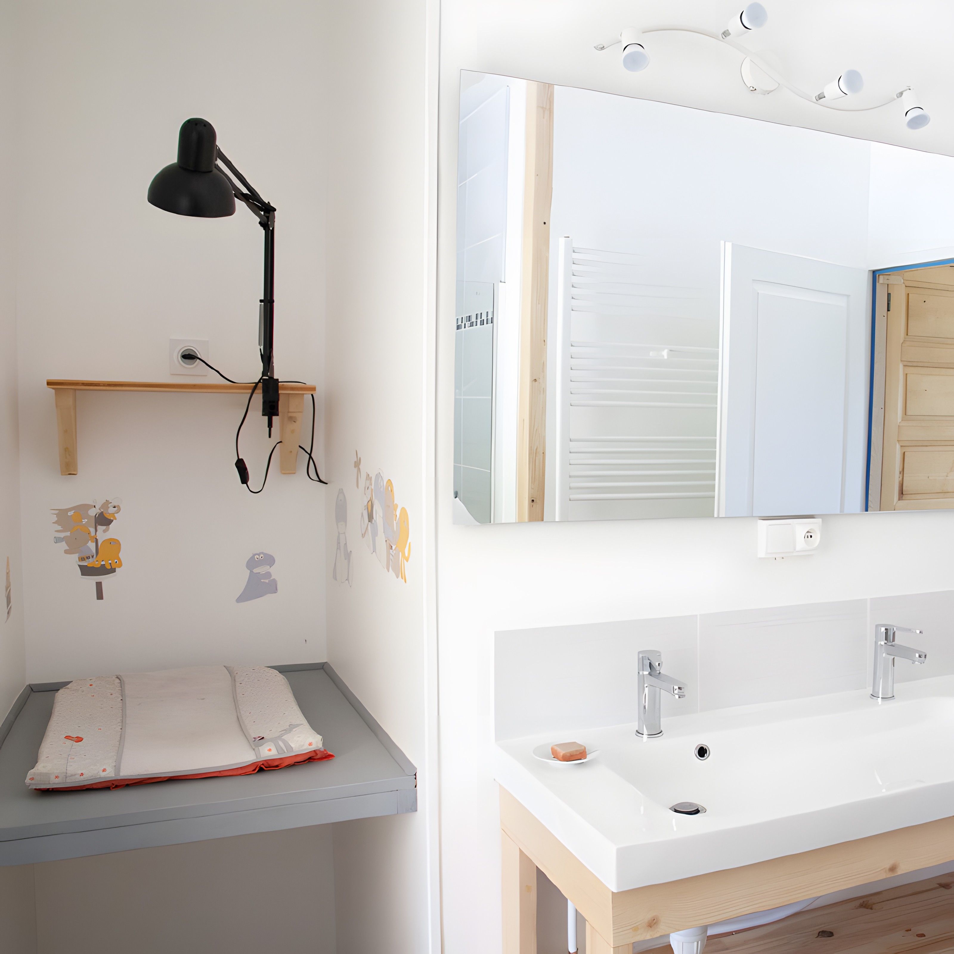 Une chambre d’enfant avec un bureau, une lampe fixée au mur et des autocollants décoratifs sur les murs.