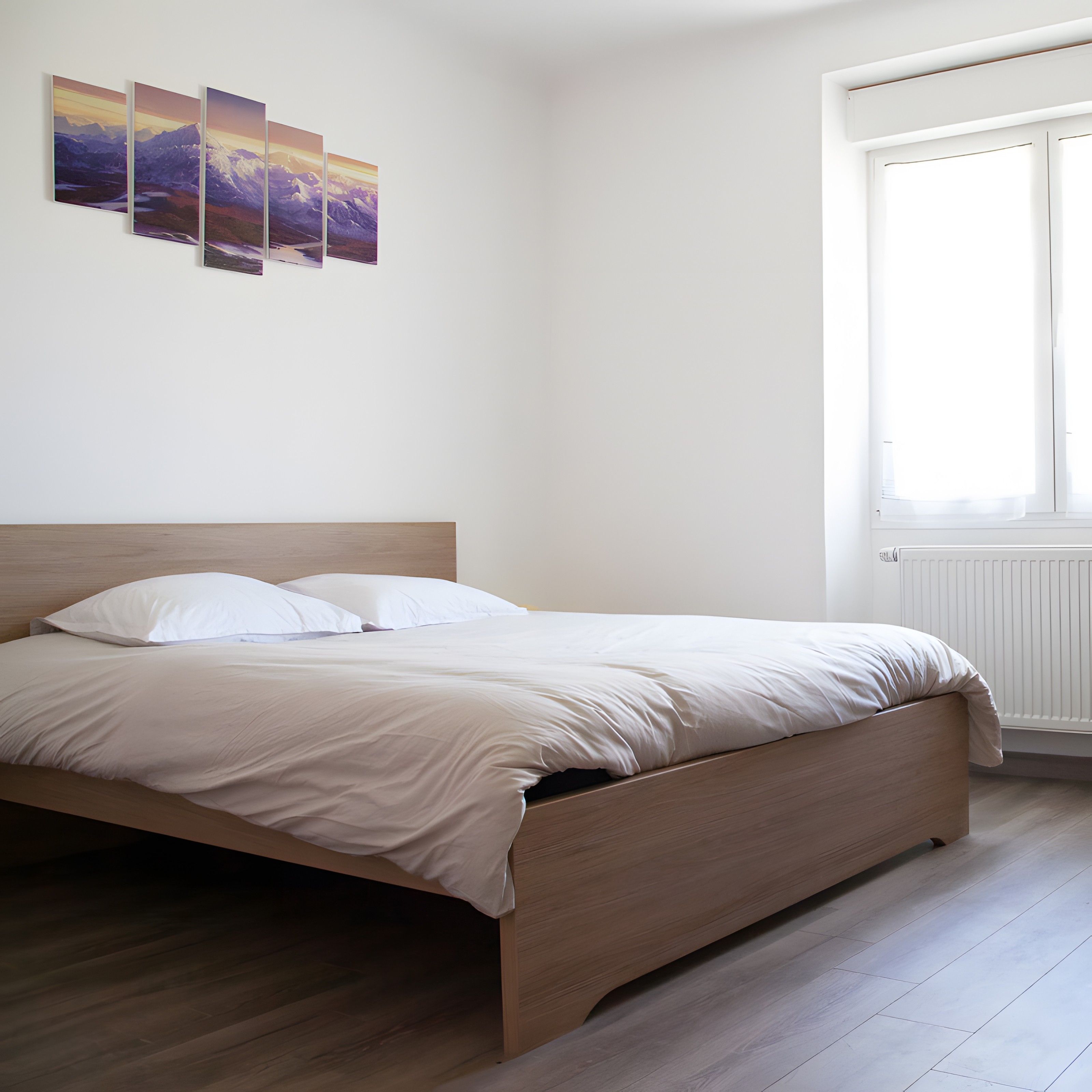 Een slaapkamer met een bed, een raam en een kunstwerk aan de muur.