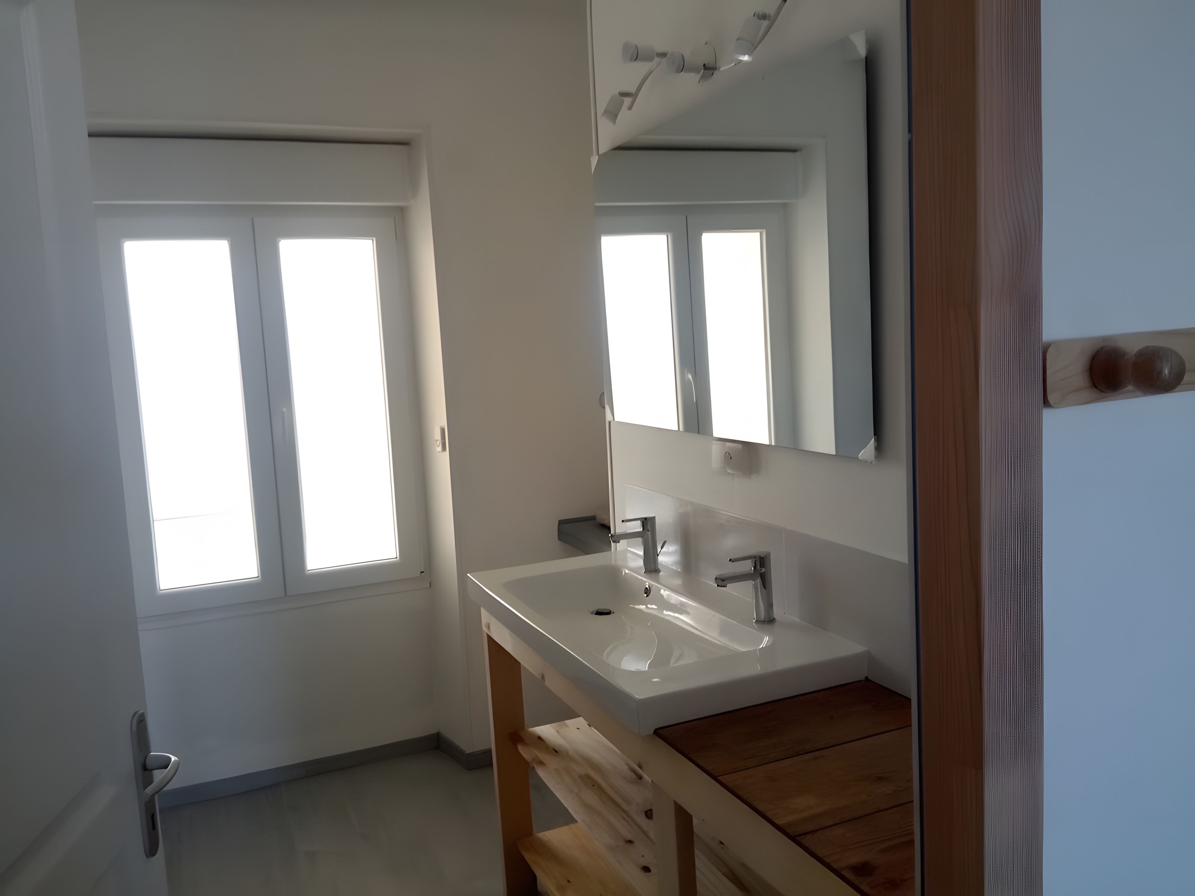 Ein Badezimmer mit einem weißen Waschbecken, einer Holz-Kommode und einem Spiegel.