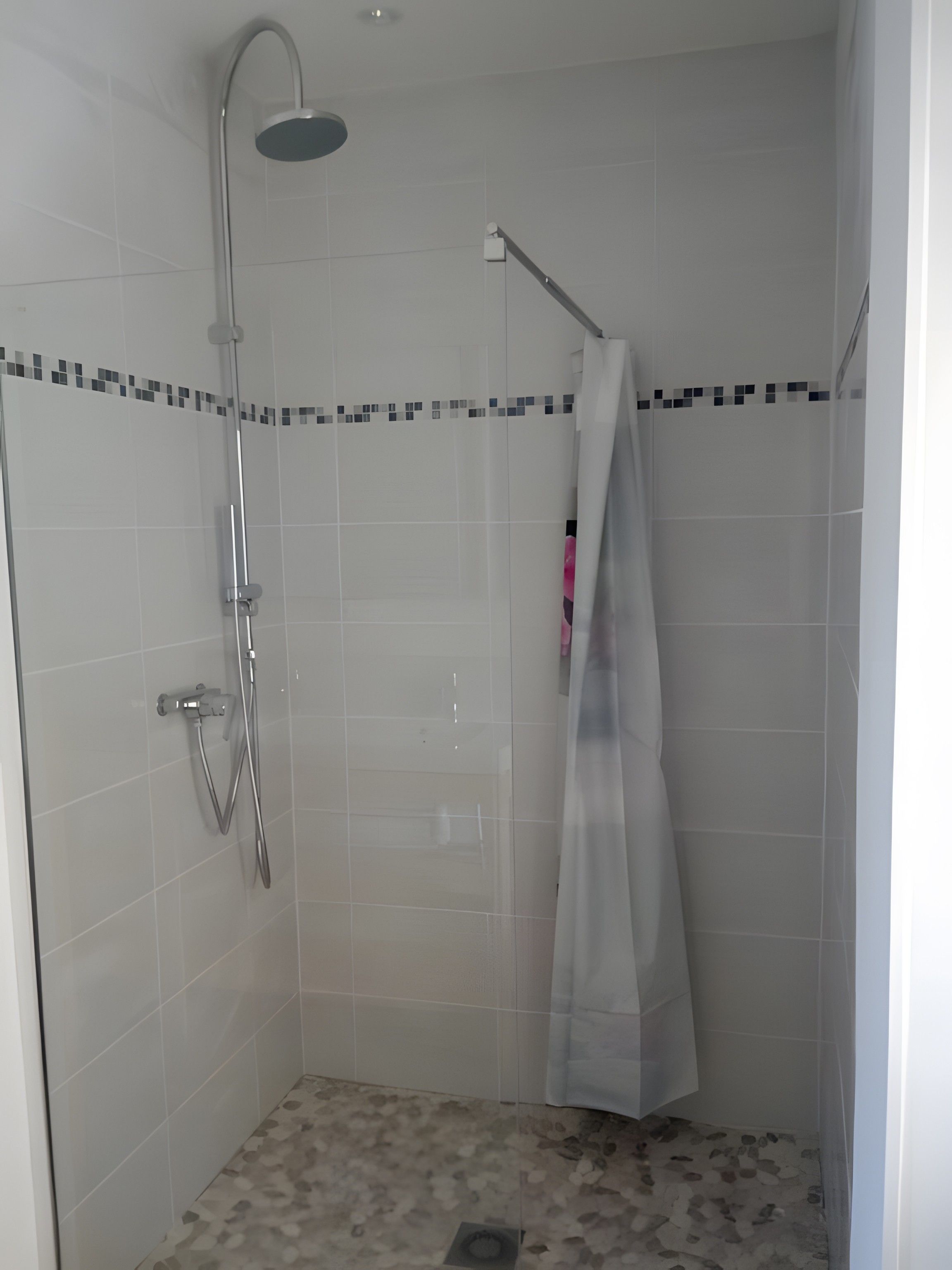 Une douche équipée d’un pommeau de douche à main et d’un robinet fixé au mur.