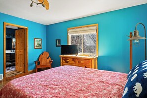 A bedroom with a bed, a dresser, a television, and a window with a view of trees. - MACKINAW STRAITS & BRIDGE VIEW 4 BEDROOM PRIVATE CABIN & BEACH (Cheboygan)