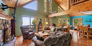 A spacious living room with a high ceiling, wooden beams, and large windows. - MACKINAW STRAITS & BRIDGE VIEW 4 BEDROOM PRIVATE CABIN & BEACH (Cheboygan)