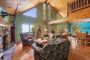 A spacious living area with a high ceiling, large windows, and a stone fireplace. - MACKINAW STRAITS & BRIDGE VIEW 4 BEDROOM PRIVATE CABIN & BEACH (Cheboygan)