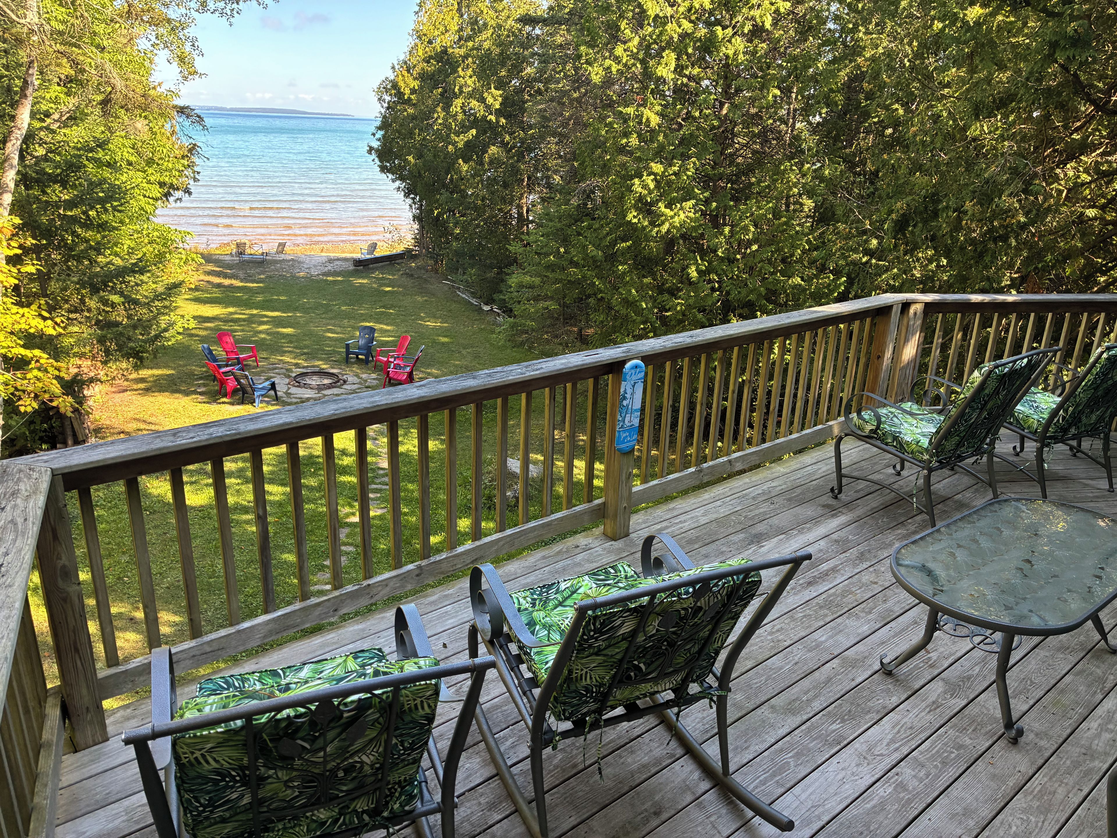 A deck with outdoor furniture overlooking a grassy area and a body of water.