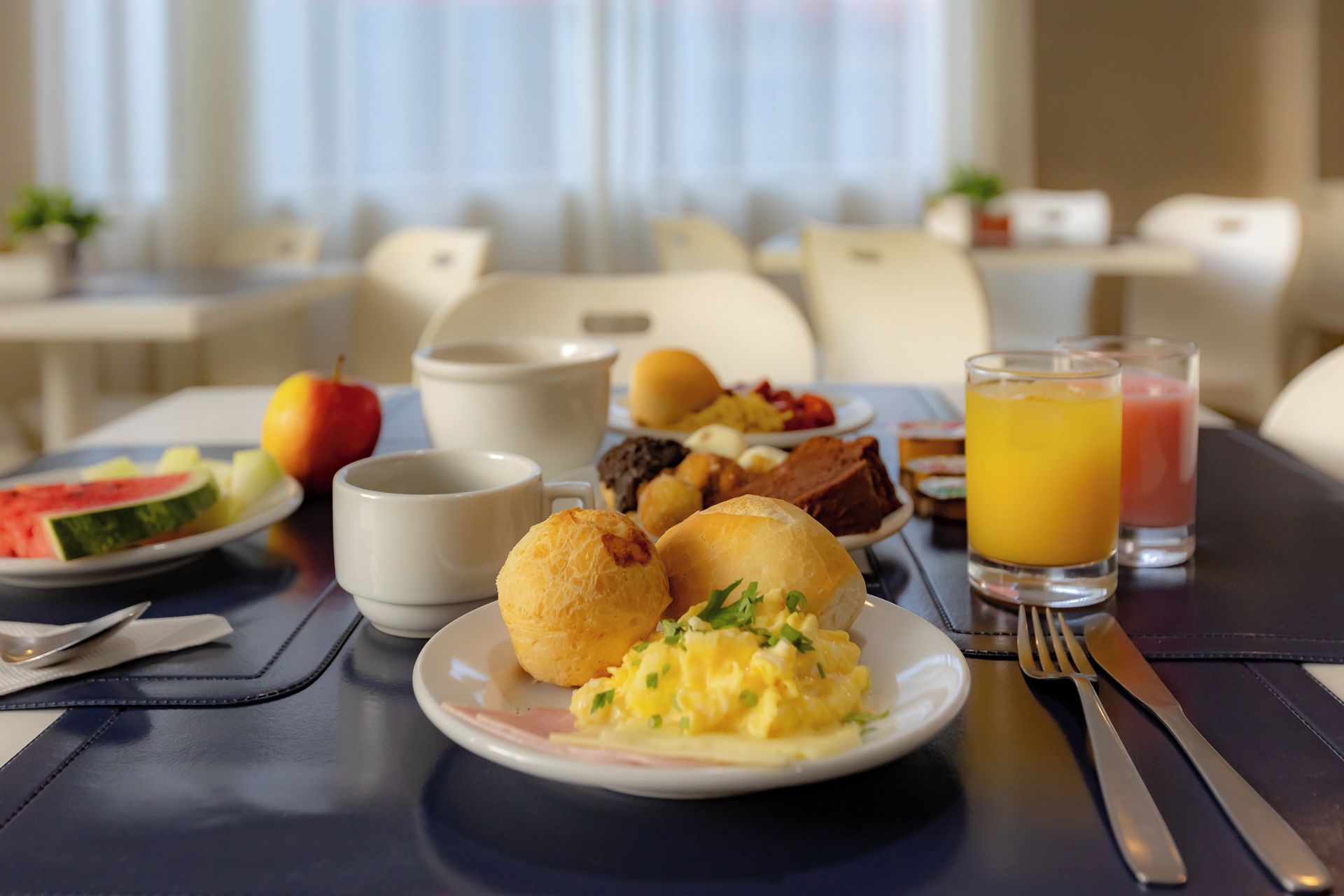 Desayuno con huevos revueltos, tostadas y un vaso de jugo de naranja.