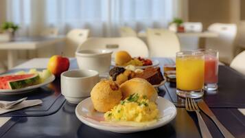 Desayuno con huevos revueltos, tostadas y un vaso de jugo de naranja.