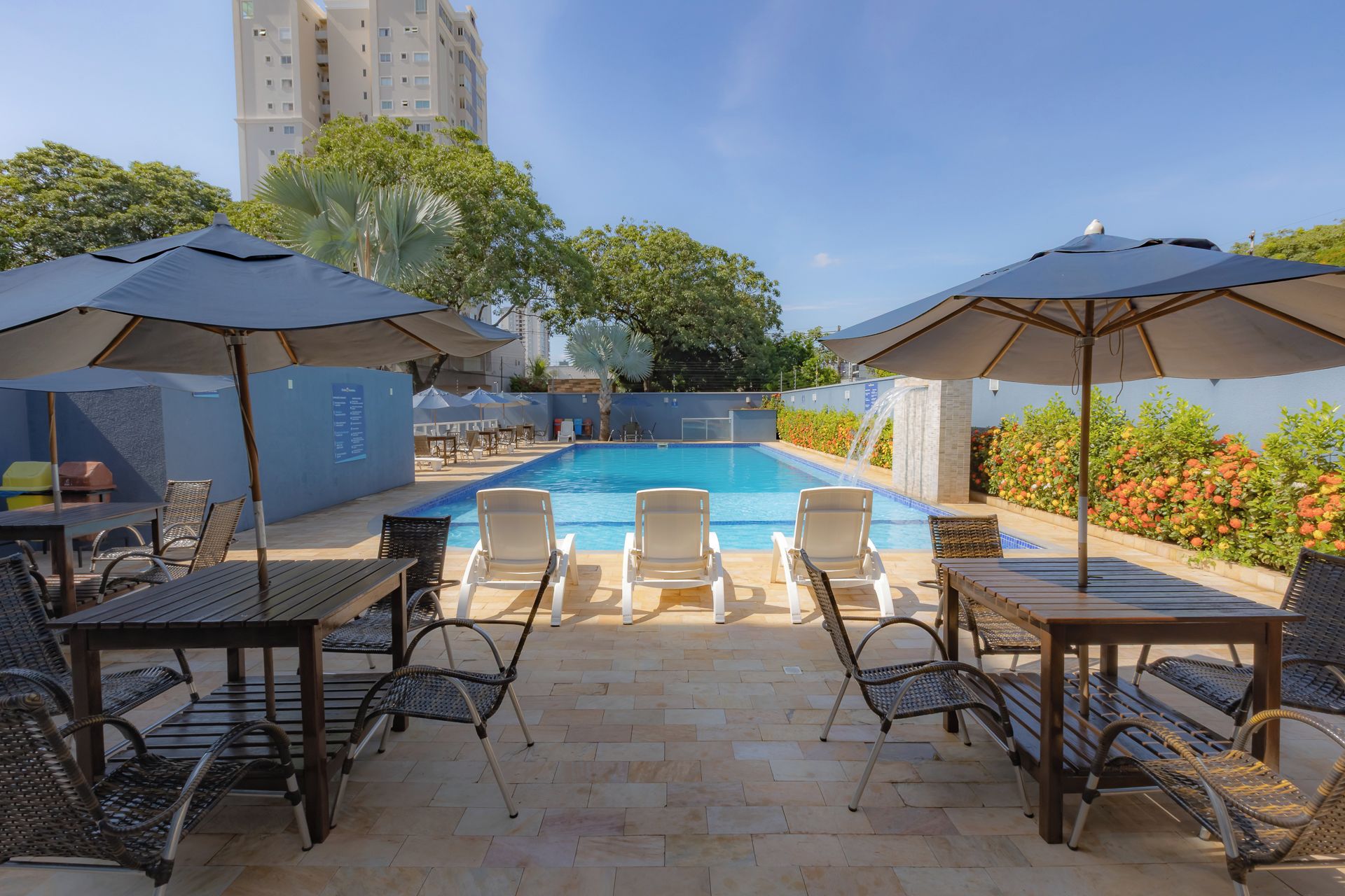 A poolside area with lounge chairs, umbrellas, and a pool.