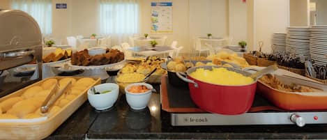Un bufé con diferentes opciones de comida y una cafetera.
